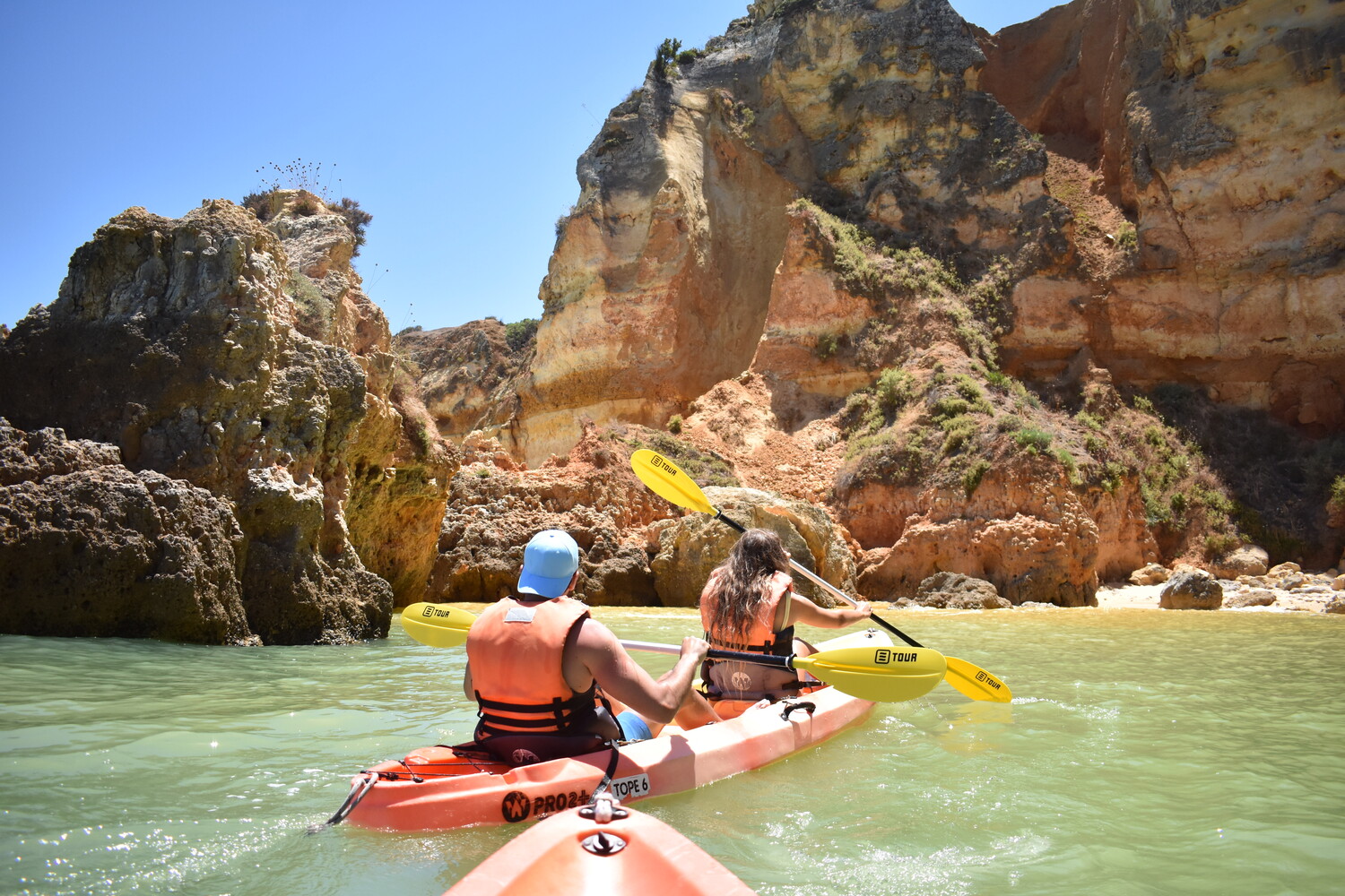 A remar junto a grandes formações rochosas no mar.